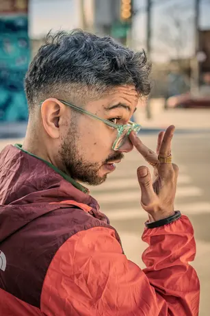 A very cool man adjusting his glasses in a very cool neighborhood in Brooklyn, New York